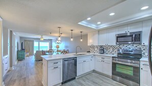 A modern kitchen with white cabinets, stainless steel appliances, and a tiled backsplash.