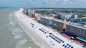 A coastal hotel with a beach view, multiple floors, and a pool area.