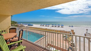 Ein Balkon mit Blick auf Strand, Pool und Liegestühle.