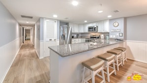 A modern kitchen with white cabinets, granite countertops, and a stainless steel refrigerator.