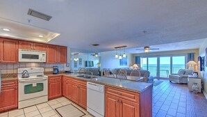 Una cocina moderna con armarios de madera, microondas integrado y lavavajillas. Cuenta con un comedor con mesa y sillas, además de un balcón con vistas.