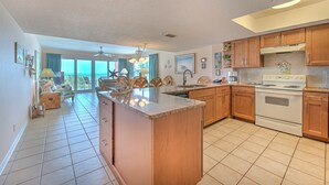 A spacious kitchen with wooden cabinets, a central island, and a large window overlooking a balcony.