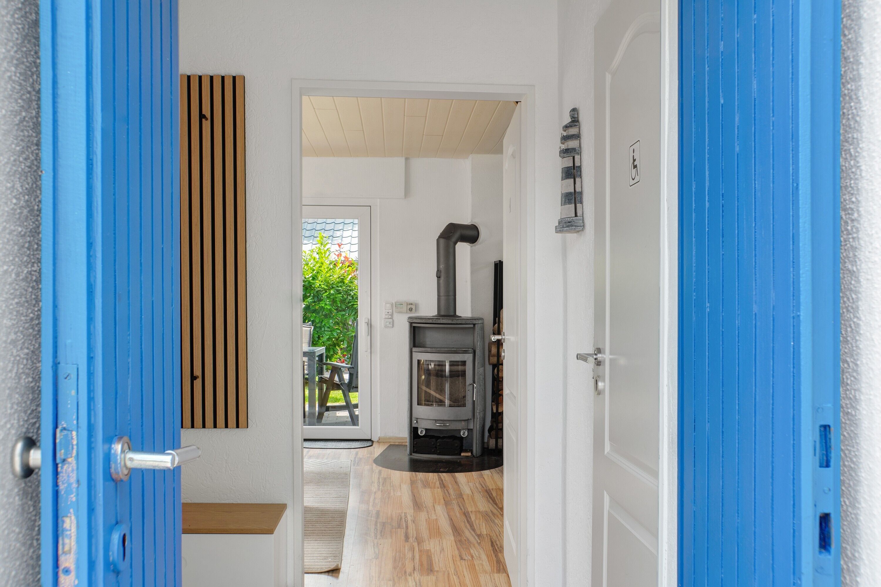 A hallway with a blue door, a wooden slat wall, a glass door leading outside, and a wood-burning stove.