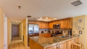 Una cocina con armarios de madera, encimera de granito, electrodomésticos de acero inoxidable y suelo de baldosas.