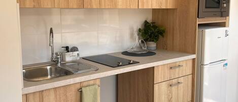 Una cocina moderna con armarios de madera, un lavamanos de acero inoxidable, un microondas y un refrigerador.