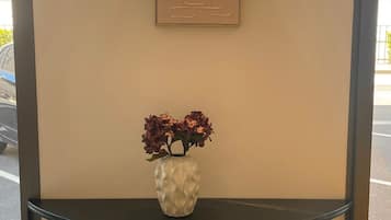 Una lámpara de pared, una obra de arte abstracta enmarco y un florero con flores sobre una consola.