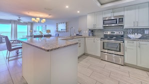 A modern kitchen with white cabinets, stainless steel appliances, and a large island.