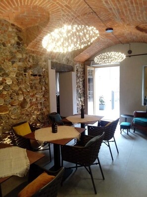 A dining area with stone walls, a chandelier, and a view of the outdoors. - Decanter House (Borgomanero)