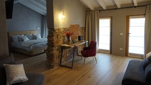Una habitación acogedora con una cama, una silla roja, una pequeña mesa con un florero y una pared de piedra.