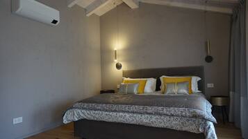 Un dormitorio con una cama grande, una mesita de noche, aire acondicionado de pared y una lámpara colgante.