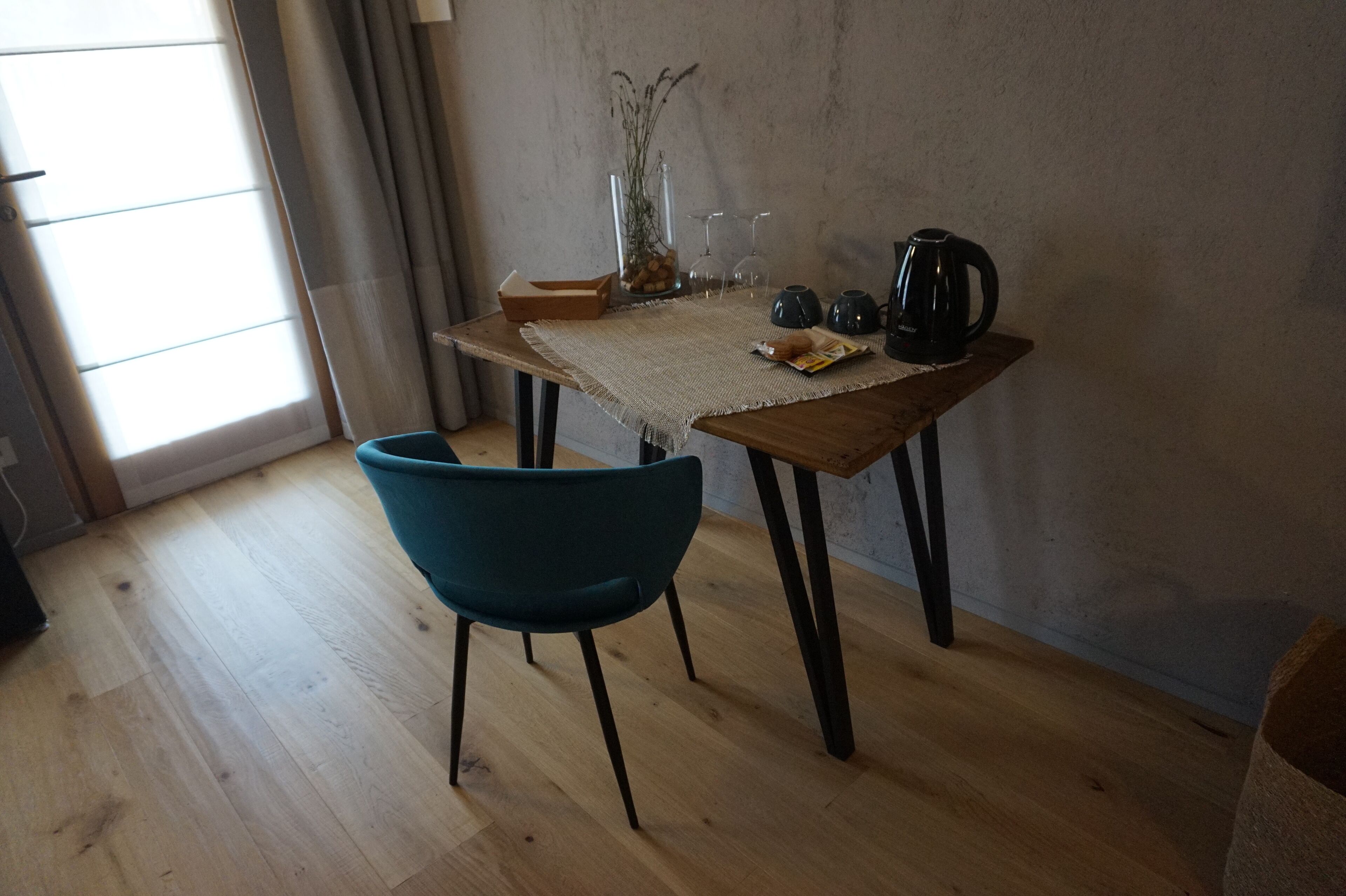 A room with a wooden table, a blue chair, and a window with curtains.