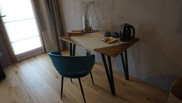 A room with a wooden table, a blue chair, and a window with curtains.
