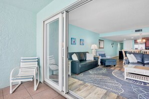 Ein Wohnzimmer mit einer Schiebetür zum Glasbalkon, einer Couch, einem Couchtisch und einem Essbereich mit Stühlen.