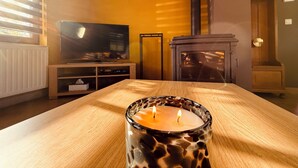 Una sala de estar con televisión, chimenea y una mesa con vela.