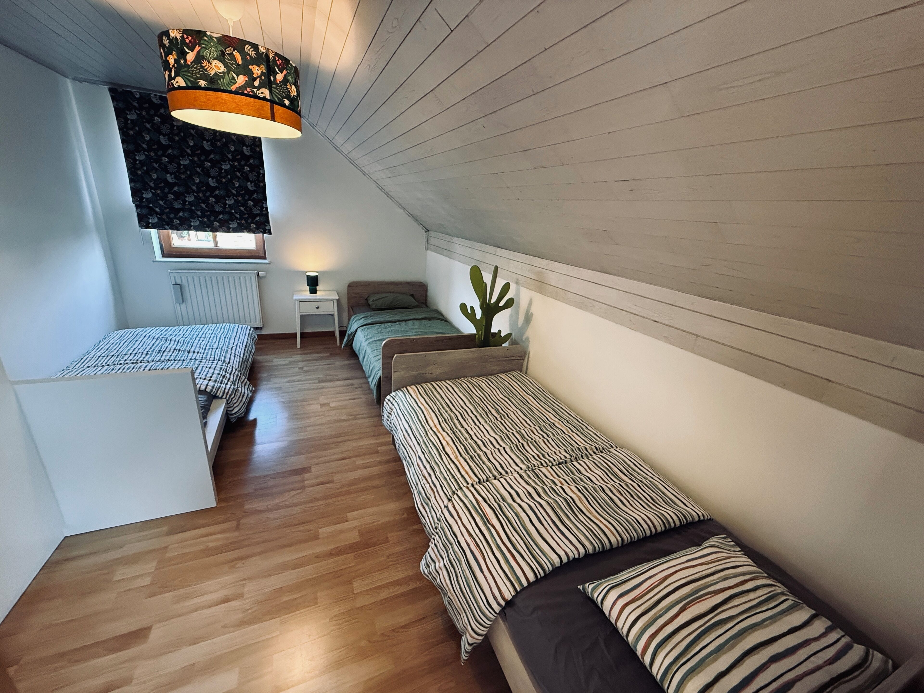 Une chambre de dortoir avec deux lits, une petite table, une lampe et une plante en pot.