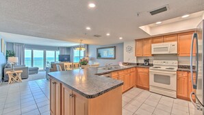 A modern kitchen with granite countertops, wooden cabinets, a stainless steel refrigerator, and a built-in oven.