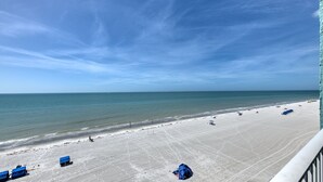 A beach with a clear sky, a sandy shore, and a few blue structures.