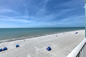 A beach with a clear sky, a sandy shore, and a few blue structures.