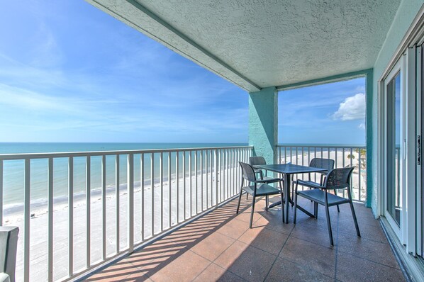 A balcony with a view of the beach and ocean.