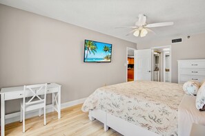 Un dormitorio con cama, escritorio y ventilador de techo.