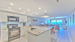 Una cocina moderna con electrodomésticos de acero inoxidable, una isla grande y vista al área de estar.