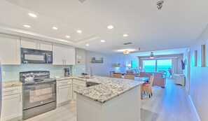 Una cocina moderna con electrodomésticos de acero inoxidable, una isla grande y vista al área de estar.