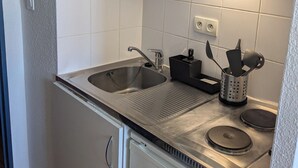 A compact kitchen with a stainless steel sink, a microwave, and a small stove. - Studio at the gates of the Avignon ramparts (Avignon)