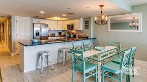 A modern kitchen with a central island, bar stools, and a dining area with a table and chairs.