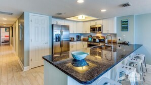 A modern kitchen with white cabinets, stainless steel appliances, and a granite countertop.