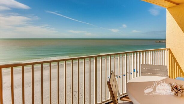 A balcony with a view of the beach and ocean.