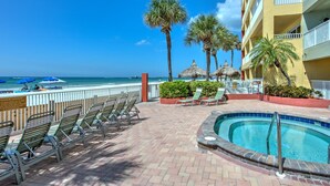 A poolside area with lounge chairs, a pool, and a view of the beach.