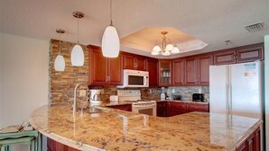 A kitchen with granite countertops, a built-in microwave, a stove, and wooden cabinets.