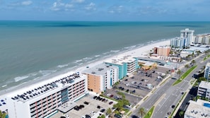 Un hotel frente al mar con varios pisos, aparcamiento y vistas a la playa y al océano.