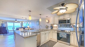 Una cocina moderna con una isla central, electrodomésticos de acero inoxidable e iluminación colgante.