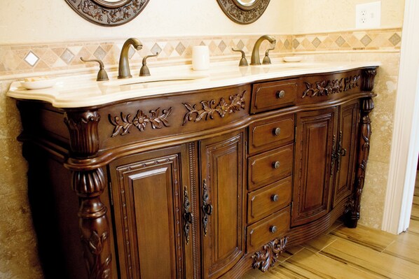 Un tocador de madera con encimera de mármol, varios cajones y un espejo sobre el lavabo.