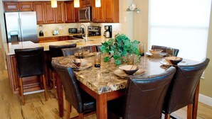 A modern kitchen with wooden cabinets, stainless steel appliances, and a marble countertop.