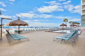 A poolside area with lounge chairs, umbrellas, and a view of the ocean. - Top Floor Gulf Front Condo w/ Big Balcony - RS614 (N. Redington Beach)