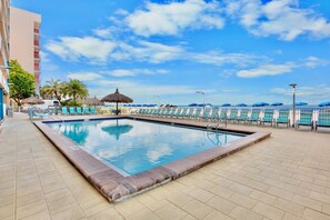 A swimming pool with lounge chairs, a thatched umbrella, and a view of the ocean. - Top Floor Gulf Front Condo w/ Big Balcony - RS614 (N. Redington Beach)