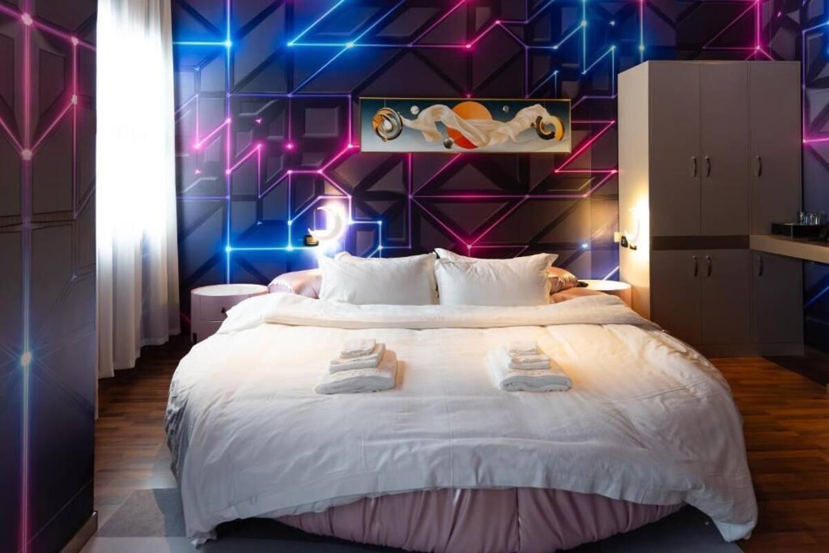 A modern bedroom with a large bed, a bedside table, and a wardrobe.