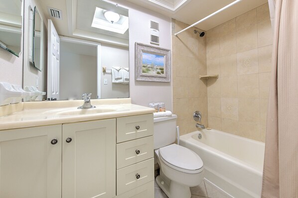 A bathroom with a sink, mirror, toilet, and bathtub.