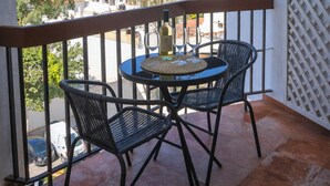 A balcony with a table and chairs, overlooking a residential area.