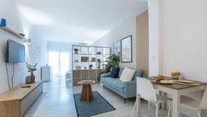 A modern living room with a sofa, coffee table, and dining area with chairs.