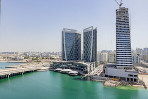 A modern building complex with a waterfront view, featuring two prominent towers and a large building with a unique facade.