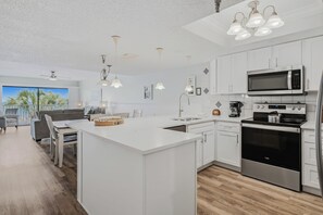 A modern kitchen with white cabinetry, stainless steel appliances, and pendant lighting.