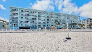 A beachfront hotel with multiple balconies, a sandy beach, and a clear sky.
