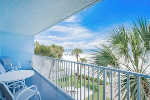 A balcony with white railings, a table, and chairs.