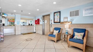 A lobby with wicker chairs, a reception desk, and a sign reading 'SAND DOLLAR.'