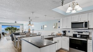 A modern kitchen with white cabinets, stainless steel appliances, and a large island. - Sand Dollar 203 is a Silver Tier 3-bedroom 2 bath Gulf Front Condo (Indian Shores)