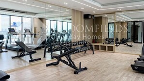Een moderne sportschool met loopbanden, krachttrainingsapparaten en losse gewichten.