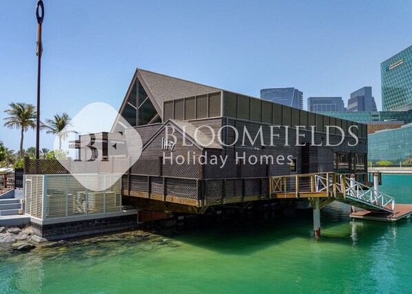 A modern holiday home with a unique architectural design, featuring a large balcony and a view of the water. - Bloomfields Skyline 1Br In Al Maryah Island (Abu Dabi)
